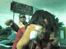 a man with dreadlocks is talking on a cell phone in front of a billboard that says ' texas '