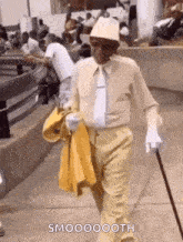 a man in a suit is walking down the street with a cane .