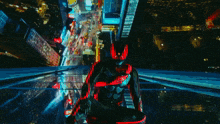 a man in a black and red superhero costume is looking down at a city