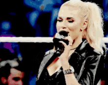 a woman in a black leather jacket is singing into a microphone .