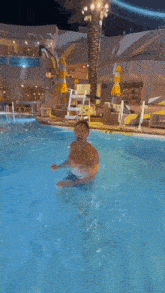 a man without a shirt is swimming in a swimming pool