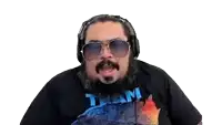 a man with a beard wearing headphones and sunglasses is wearing a team shirt .
