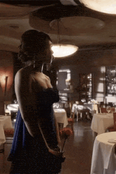 a woman in a blue dress is holding a flower in a restaurant .