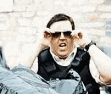 a man wearing sunglasses covering his ears while laying on a bag