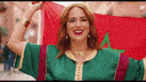 a woman in a green and gold dress holds a red flag