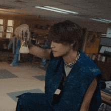 a person in a blue vest is holding a beaker