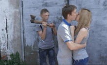a boy is holding an axe while a girl kisses a man