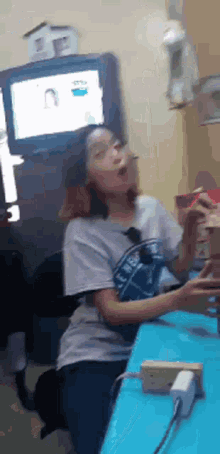 a girl wearing a shirt that says ' i love you ' on it sits at a desk