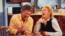 a man and a woman are sitting at a table laughing
