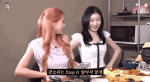 two women are sitting at a table with plates of food and a sign that says stop it .