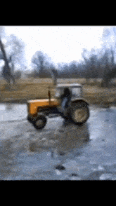 a yellow tractor is driving through a frozen field