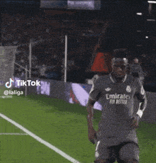 a soccer player wearing a jersey that says emirates fly better is dancing on the field