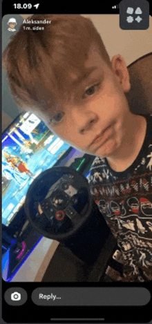 a young boy is holding a steering wheel in front of a video game screen .
