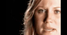 a close up of a woman 's face with a black background making a funny face .