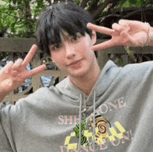 a young man wearing a hoodie that says she gone dance on is giving a peace sign