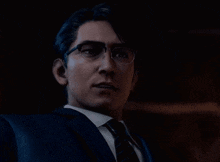 a man wearing glasses and a suit is looking at the camera