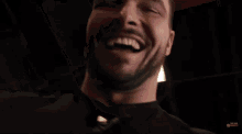 a man with a beard is laughing in a dark room with a light behind him .