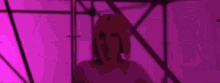 a woman with blue hair is dancing in a purple lighted room .