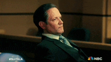 a man in a suit and tie is sitting in a courtroom with #suitsla written on the bottom