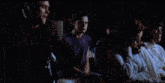 a group of people sitting in chairs in a dark room in a movie .