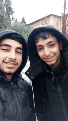 two young men are posing for a picture with one wearing a hood
