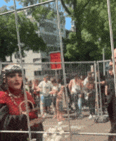 a woman in a red dress is standing in front of a fence with a red sign that says no entry