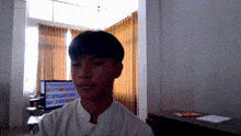 a man in a white shirt is standing in front of a computer screen