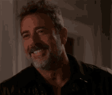 a man with a beard and mustache is smiling for the camera .