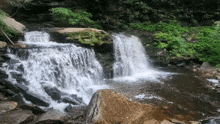 a waterfall is surrounded by rocks and greenery