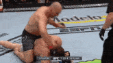 a man is kneeling down in a boxing ring while another man is standing behind him .