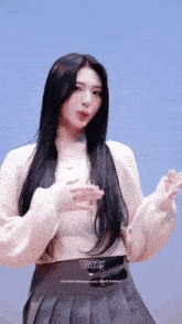 a woman with long black hair is wearing a white sweater and a gray skirt