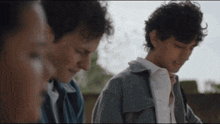 a man in a gray jacket is talking to another man in a white shirt