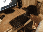 a person sitting at a desk with a keyboard and a monitor with the letter a on it