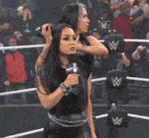 two women are standing in a wrestling ring with a w on their hat