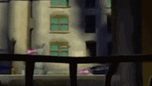 a blurry picture of a building with a balcony in the foreground and a window in the background .