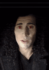 a man with curly hair has his eyes closed and is wearing a black shirt