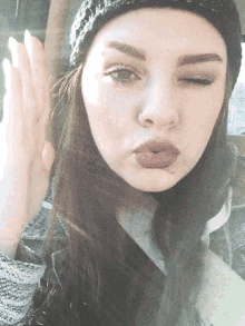 a woman wearing a black hat and red lipstick is making a face