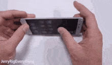 a person is holding a cell phone in their hands and pressing the screen .