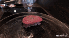 a steak is being cooked in a pan with the words made in animotica on the bottom right