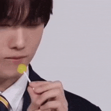 a man in a suit and tie is eating a lollipop in his mouth .