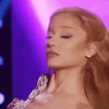 a close up of a woman 's face on a stage with purple lights in the background .