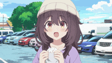 a girl in a white hat is holding a white object in front of a row of cars