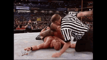 a wrestler is laying on the ground while a referee looks on during a wrestling match