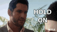 a man in a suit says hold on in white