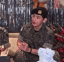 a man in a military uniform is sitting on a couch in front of a cake and balloons .