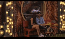 a man and a woman are sitting on a bench next to a table in a room .