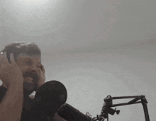 a man is singing into a microphone with his hands on his ears