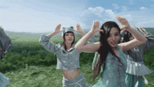 a group of women are dancing in a field with their hands in the air