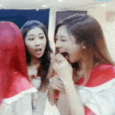 a group of young women are standing next to each other and one of them is eating a piece of food .