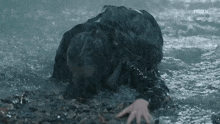 a person is crawling in the water with their hand on the ground .